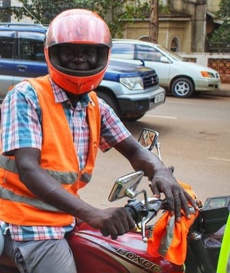 Boda boda rider in a reflective vest and helmet on his motorcycle